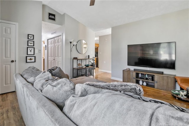 living area featuring lofted ceiling, baseboards, and wood finished floors