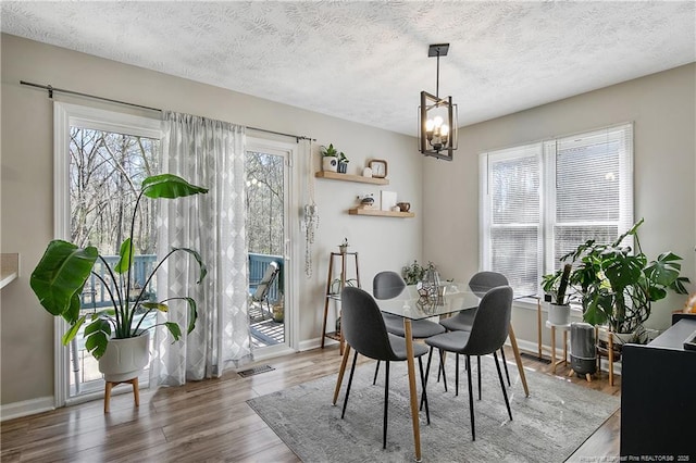 dining area featuring a textured ceiling, wood finished floors, visible vents, and a notable chandelier