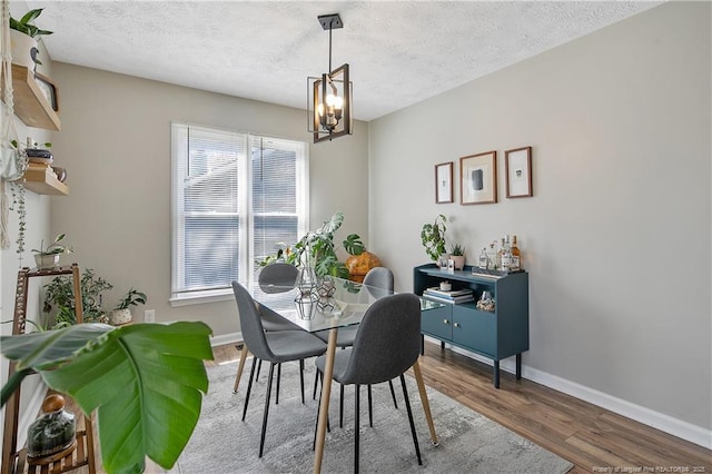 dining room with a chandelier, a textured ceiling, baseboards, and wood finished floors