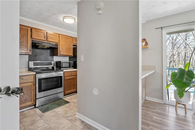 kitchen featuring a textured ceiling, appliances with stainless steel finishes, brown cabinets, and under cabinet range hood