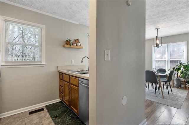 kitchen featuring light countertops, visible vents, a sink, a textured ceiling, and dishwasher