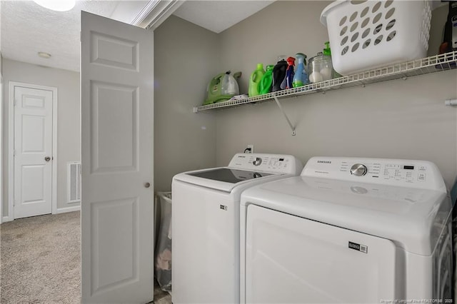 clothes washing area featuring light carpet, laundry area, visible vents, baseboards, and washing machine and dryer