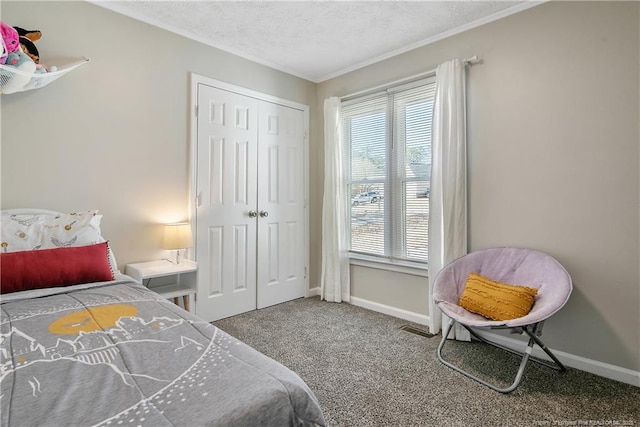 carpeted bedroom with a textured ceiling, a closet, and baseboards