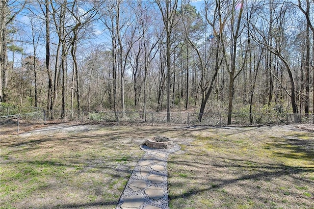 view of yard featuring a wooded view and fence