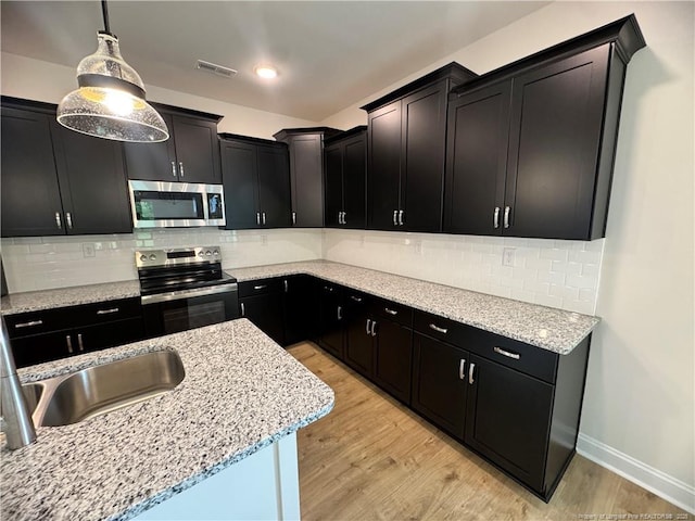 364 Whitestone Dr, Fayetteville, NC 28312 - kitchen with appliances with stainless steel finishes, dark cabinetry, light wood-type flooring, pendant lighting, and light stone counters