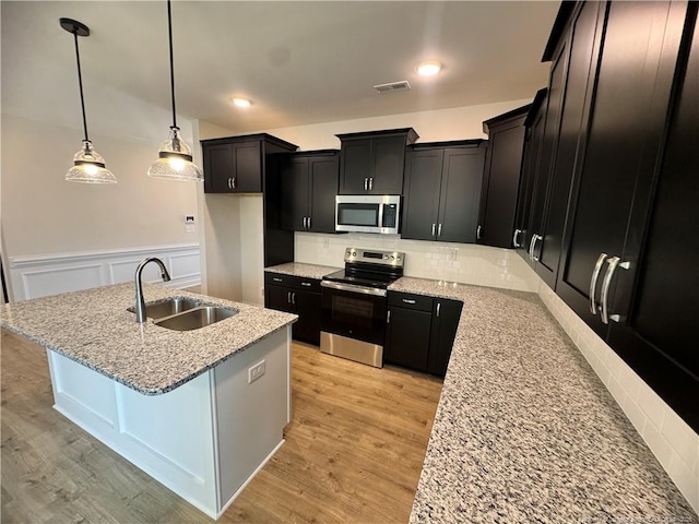 364 Whitestone Dr, Fayetteville, NC 28312 - kitchen featuring stainless steel appliances, dark cabinetry, tasteful backsplash, light stone countertops, and wainscoting