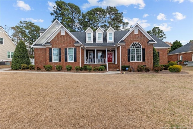 view of front of house featuring covered porch, brick siding, and a front lawn