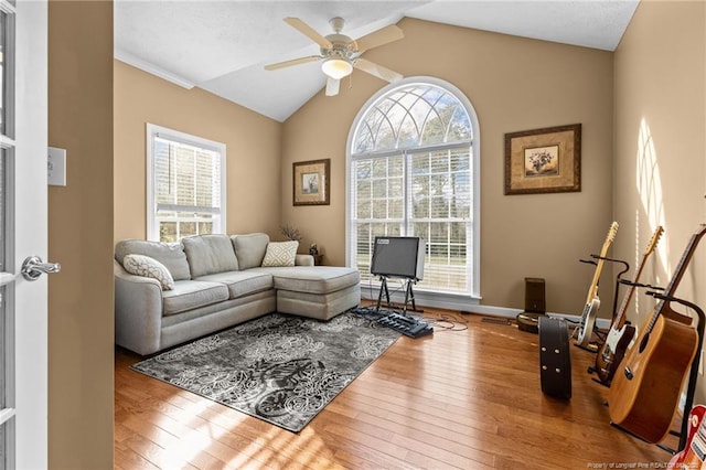 living room featuring hardwood / wood-style flooring, baseboards, vaulted ceiling, and a ceiling fan