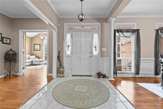 entryway with ornamental molding, wainscoting, decorative columns, and wood finished floors