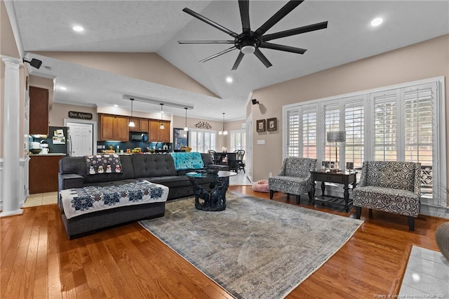 living area featuring light wood-type flooring, lofted ceiling, decorative columns, and ceiling fan