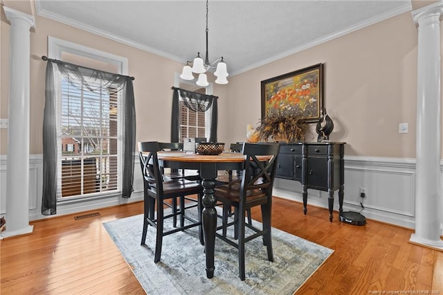 dining area with crown molding, a notable chandelier, visible vents, wood finished floors, and ornate columns