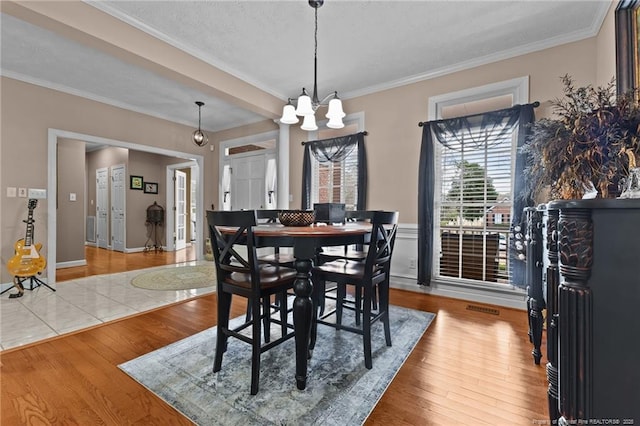 dining space featuring a chandelier, visible vents, crown molding, and wood finished floors