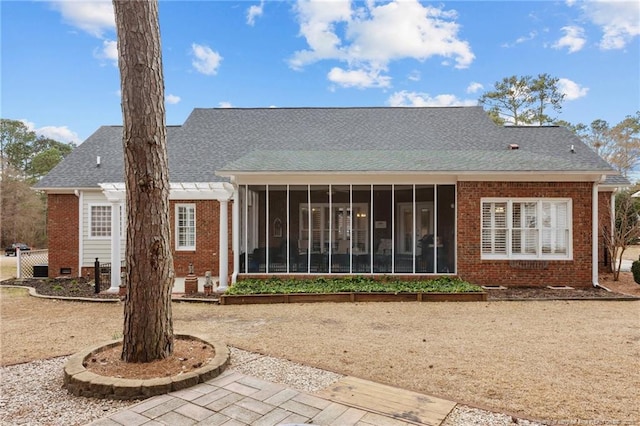 rear view of house with a sunroom, roof with shingles, and brick siding