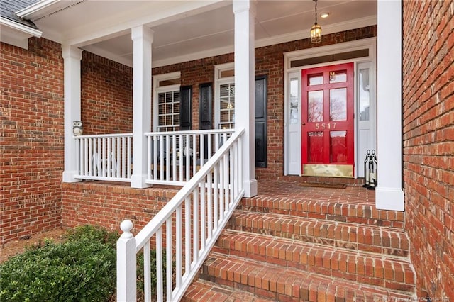 entrance to property featuring covered porch and brick siding