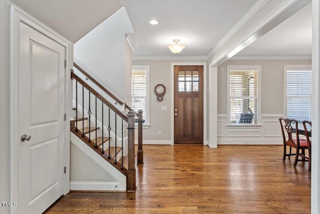 foyer with stairs, plenty of natural light, wood finished floors, and ornamental molding