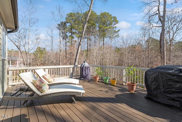 wooden deck featuring area for grilling and a forest view