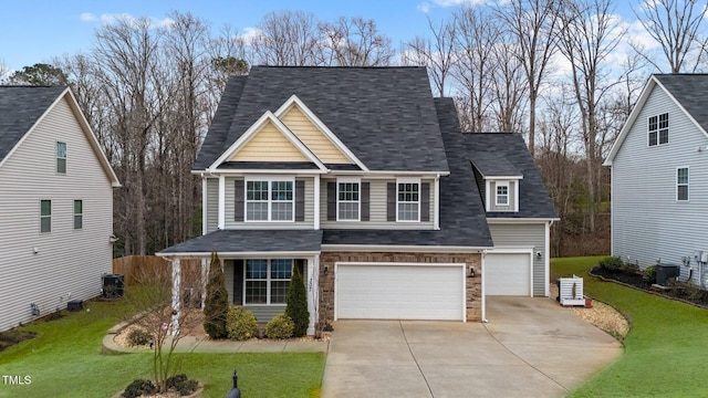 view of front of home featuring concrete driveway, a front yard, central AC, a garage, and stone siding