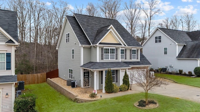 view of front facade with an attached garage, fence, a front yard, cooling unit, and driveway