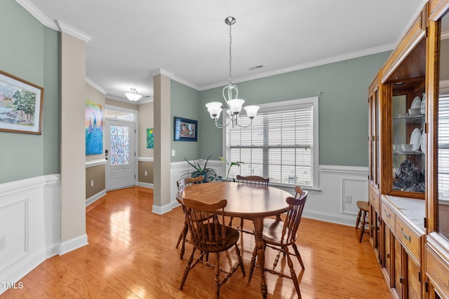 dining area with light wood-style flooring, a notable chandelier, visible vents, and wainscoting