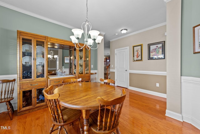 dining space with a notable chandelier, light wood-type flooring, baseboards, and ornamental molding