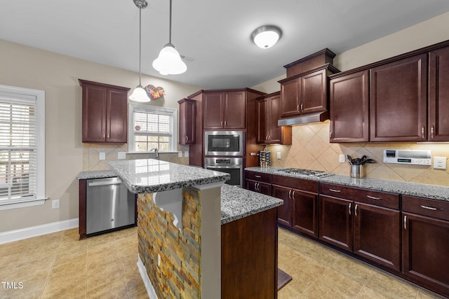 kitchen with a kitchen island, under cabinet range hood, light stone counters, decorative backsplash, and appliances with stainless steel finishes