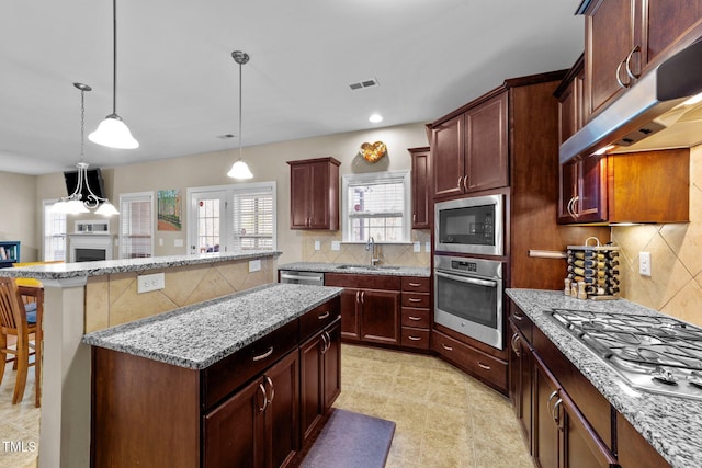 kitchen with visible vents, stainless steel appliances, decorative backsplash, under cabinet range hood, and a center island