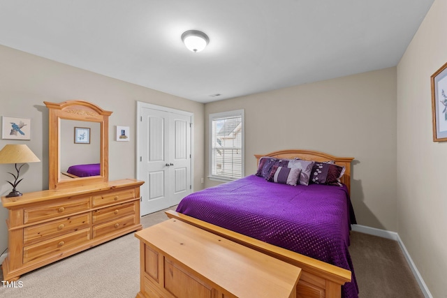 bedroom with baseboards, a closet, and light carpet