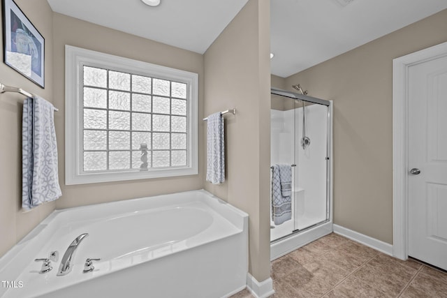 bathroom featuring tile patterned flooring, a bath, baseboards, and a stall shower