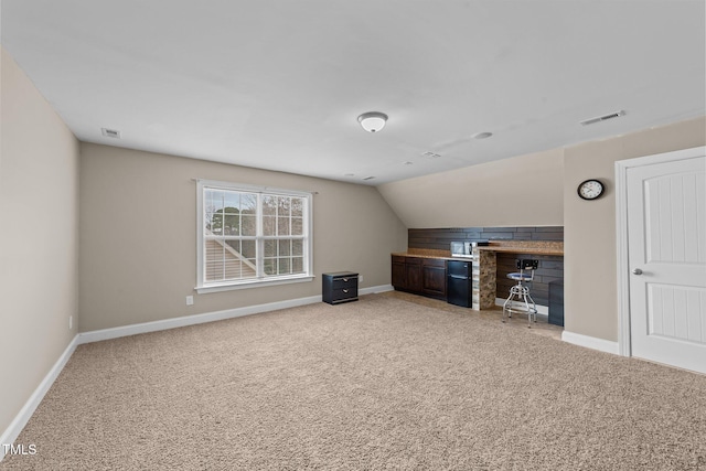 bonus room with lofted ceiling, light colored carpet, visible vents, and baseboards