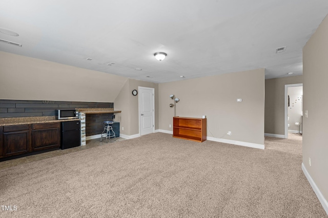 unfurnished living room featuring light carpet, visible vents, lofted ceiling, and baseboards