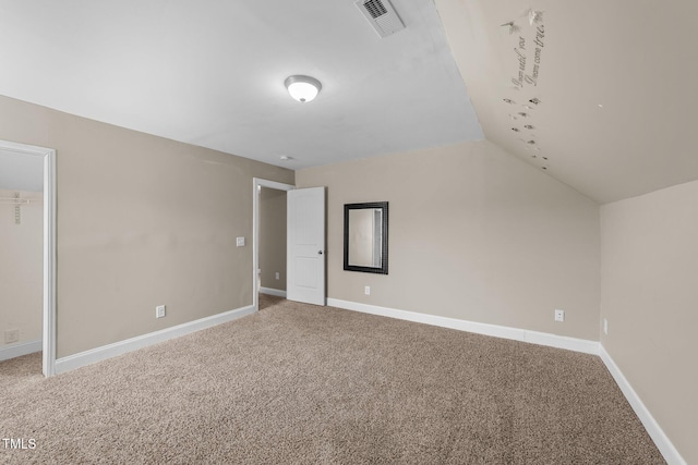 unfurnished bedroom featuring visible vents, baseboards, carpet, and lofted ceiling