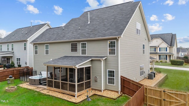 back of property featuring a gate, a fenced backyard, a yard, and a sunroom