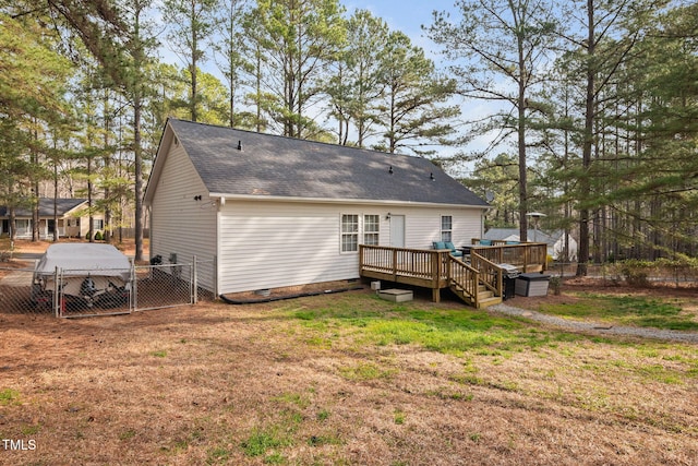 back of property with fence, a deck, a yard, crawl space, and a gate