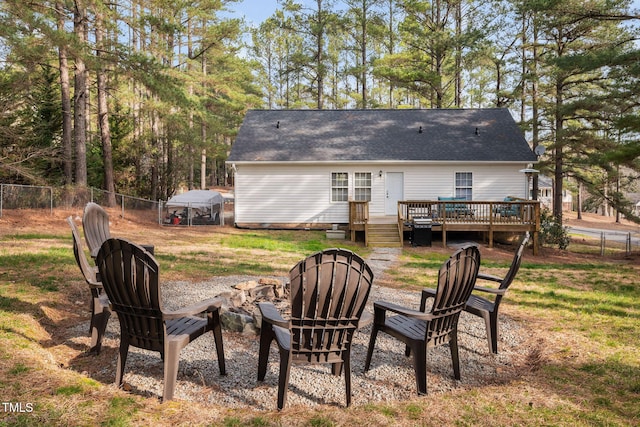 back of property featuring a shingled roof, a fire pit, fence, and a wooden deck