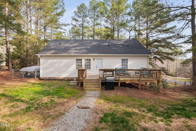 rear view of property featuring fence, a deck, a lawn, and a gate