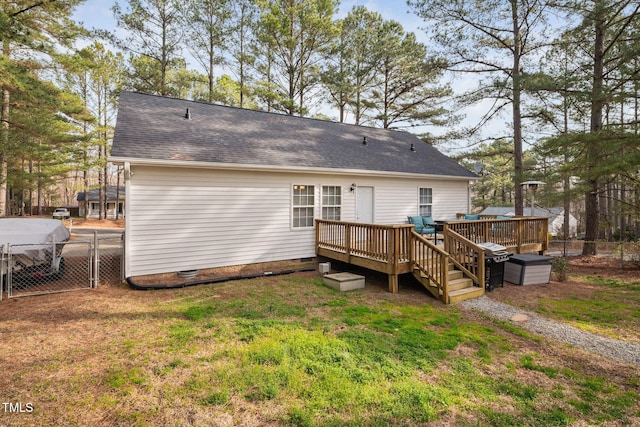 back of property featuring a deck, a gate, fence, a yard, and a shingled roof