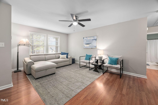 living area with baseboards, wood finished floors, and ceiling fan