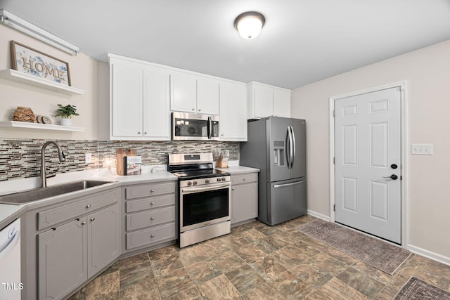 kitchen featuring white cabinetry, backsplash, appliances with stainless steel finishes, and a sink