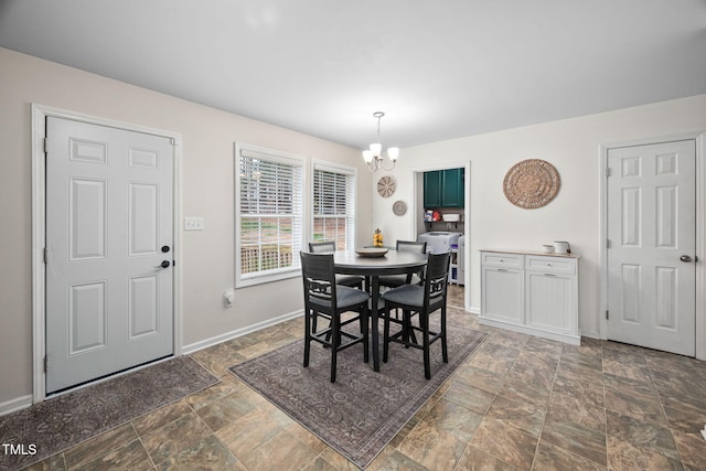 dining space featuring stone finish floor, baseboards, and a chandelier