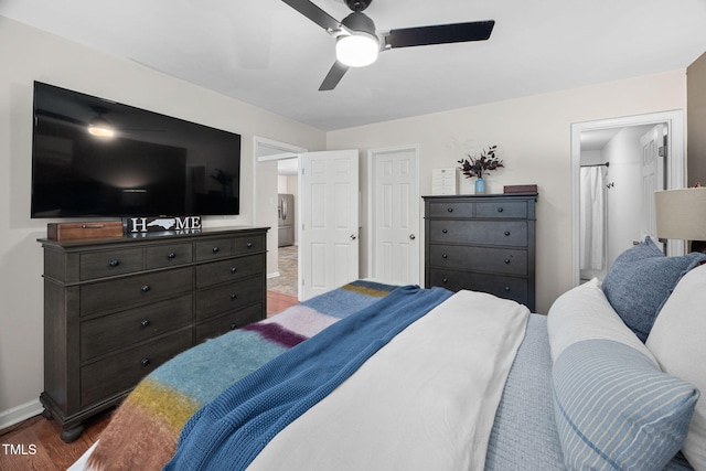 bedroom with ceiling fan, connected bathroom, baseboards, and wood finished floors