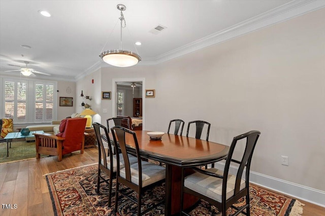 dining room with light wood-style flooring, ornamental molding, visible vents, and ceiling fan