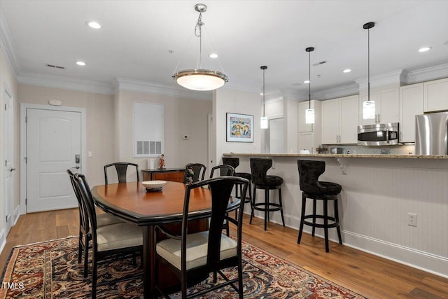 dining area with crown molding, recessed lighting, wood finished floors, and visible vents