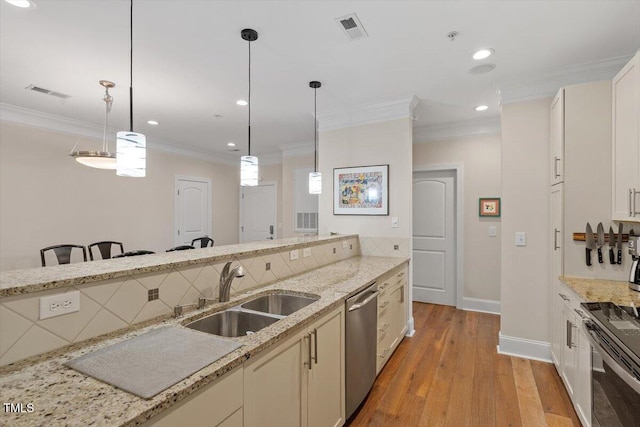 kitchen featuring a sink, stainless steel appliances, ornamental molding, and hanging light fixtures