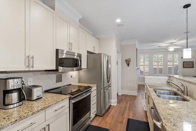 kitchen with a sink, stainless steel appliances, ornamental molding, and decorative backsplash