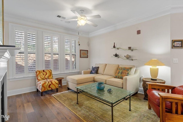 living area with hardwood / wood-style floors, a ceiling fan, baseboards, visible vents, and ornamental molding