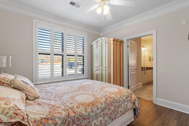 bedroom featuring visible vents, wood finished floors, connected bathroom, crown molding, and baseboards