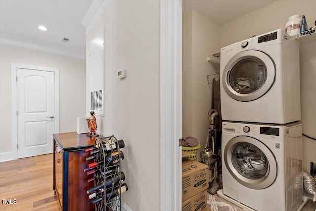 laundry area featuring light wood finished floors, laundry area, recessed lighting, ornamental molding, and stacked washer / dryer