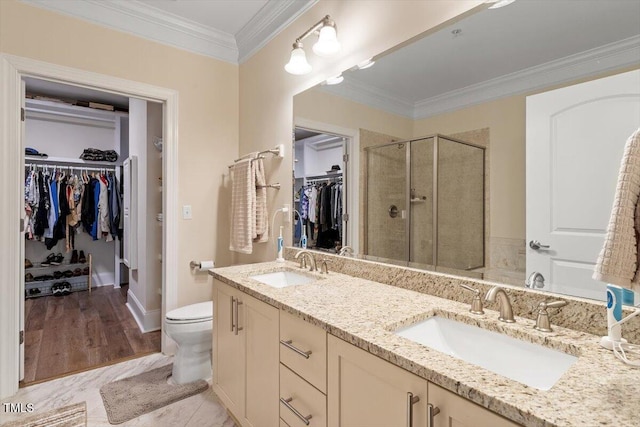 bathroom with toilet, a shower stall, ornamental molding, and a sink