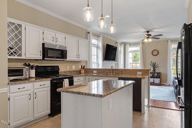 kitchen featuring a toaster, a peninsula, crown molding, black appliances, and a sink