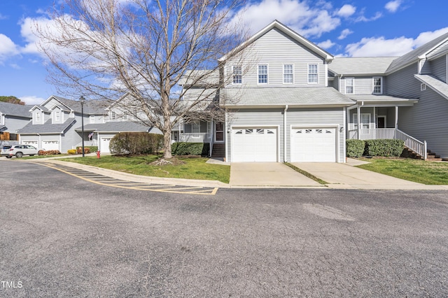 traditional home featuring driveway, a garage, a residential view, covered porch, and a front lawn